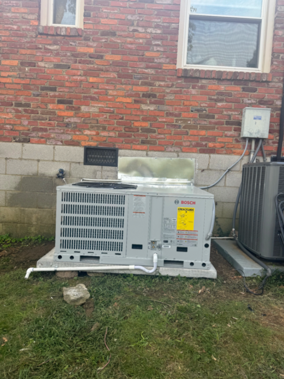 Bosch package unit installed on a concrete pad beside a brick home
