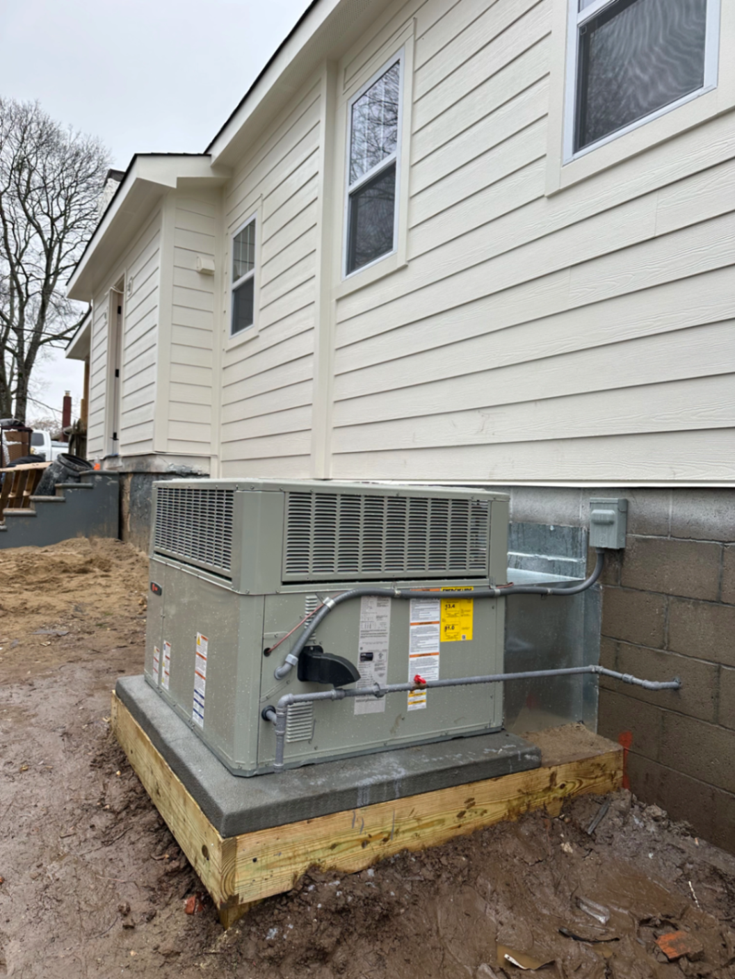 Package HVAC unit installed on a raised pad beside a newly built home