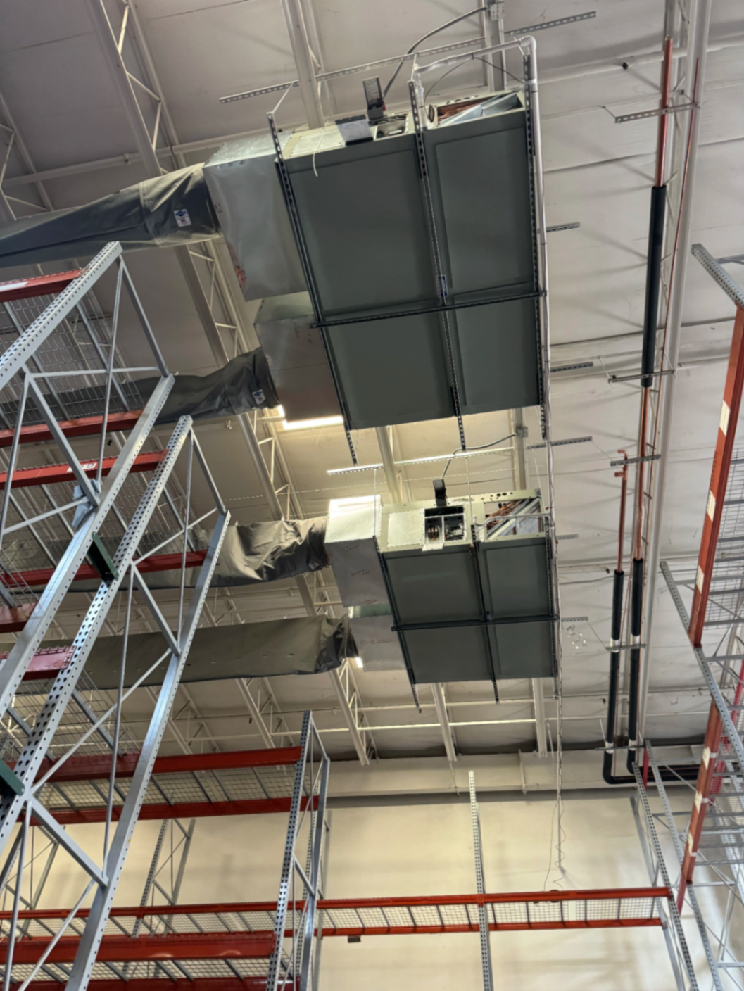Commercial ductwork suspended from the ceiling inside a warehouse building